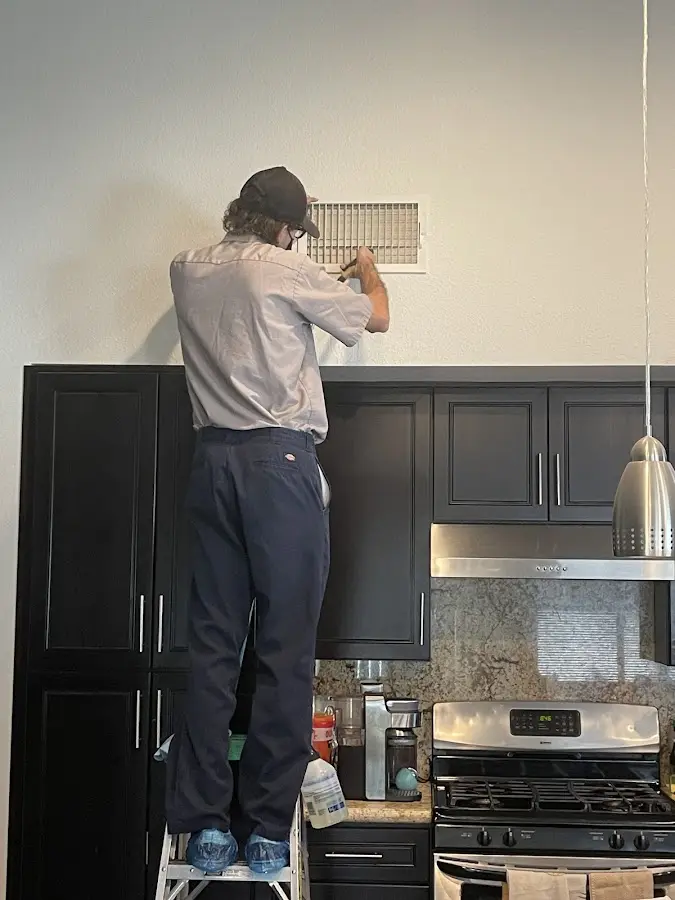 Technician inspecting an air vent during HVAC service in Hereford